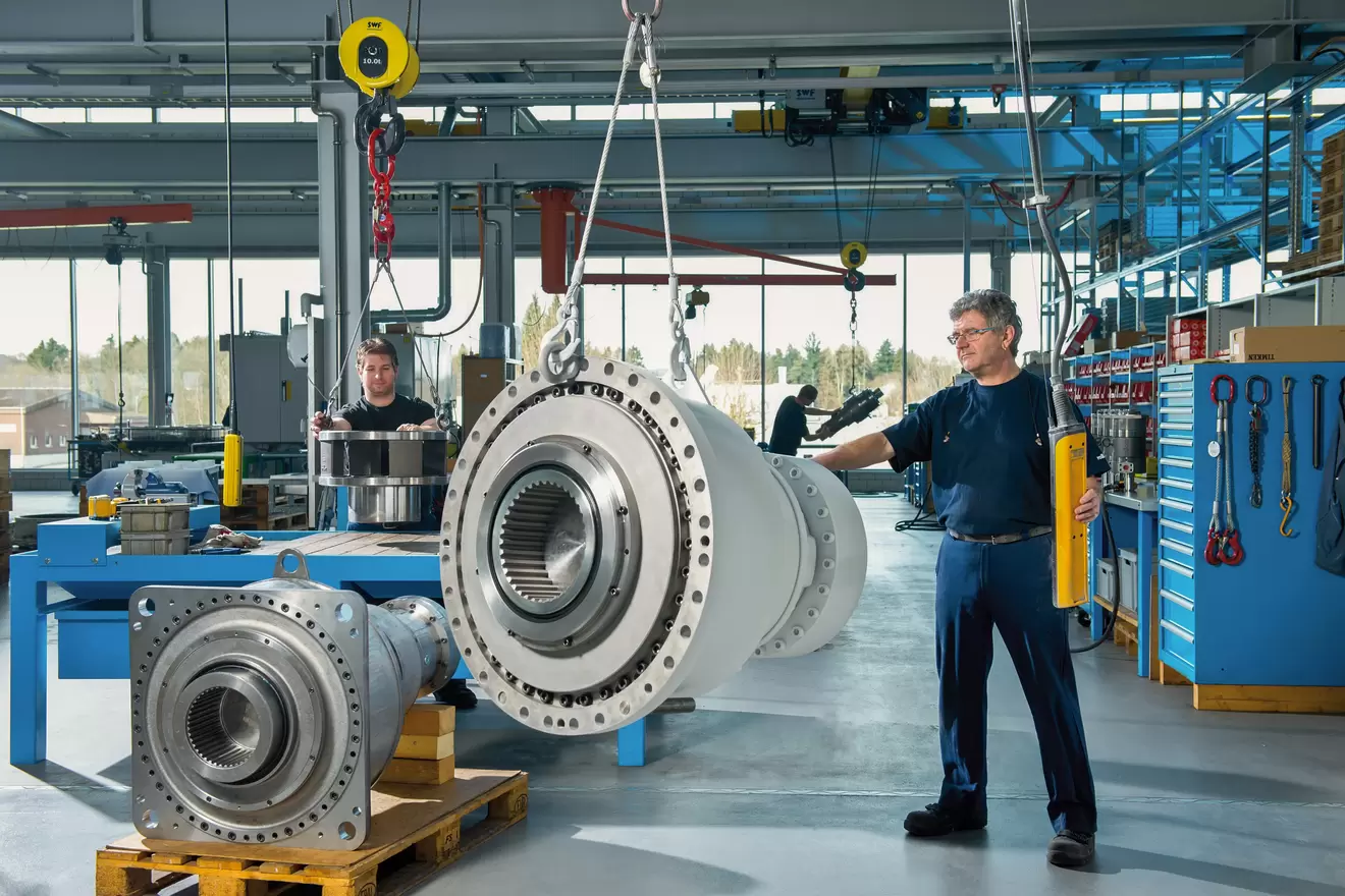 Montage eines Rollstar-Antriebsaggregats in einer Industriehalle mit Mitarbeitenden und Hebevorrichtung